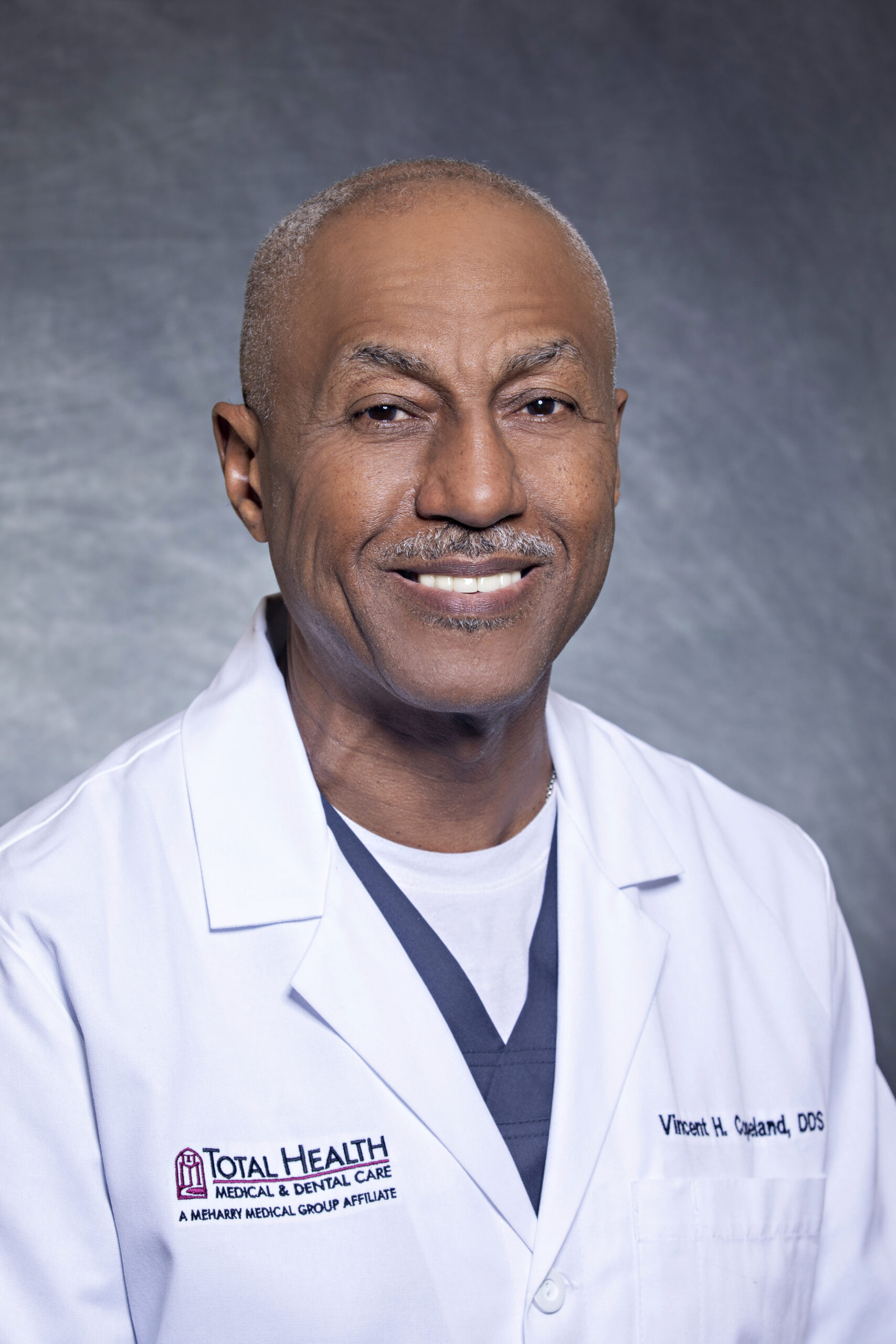 Man in white coat posing for portrait.