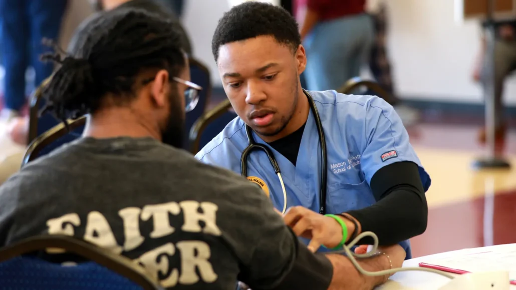 Student checking someones blood pressure.