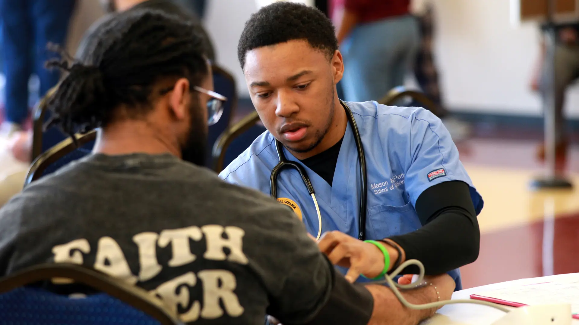Student checking someones blood pressure.