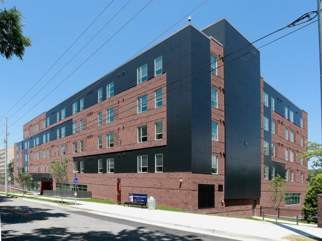 A modern apartment building with a black exterior and large windows.