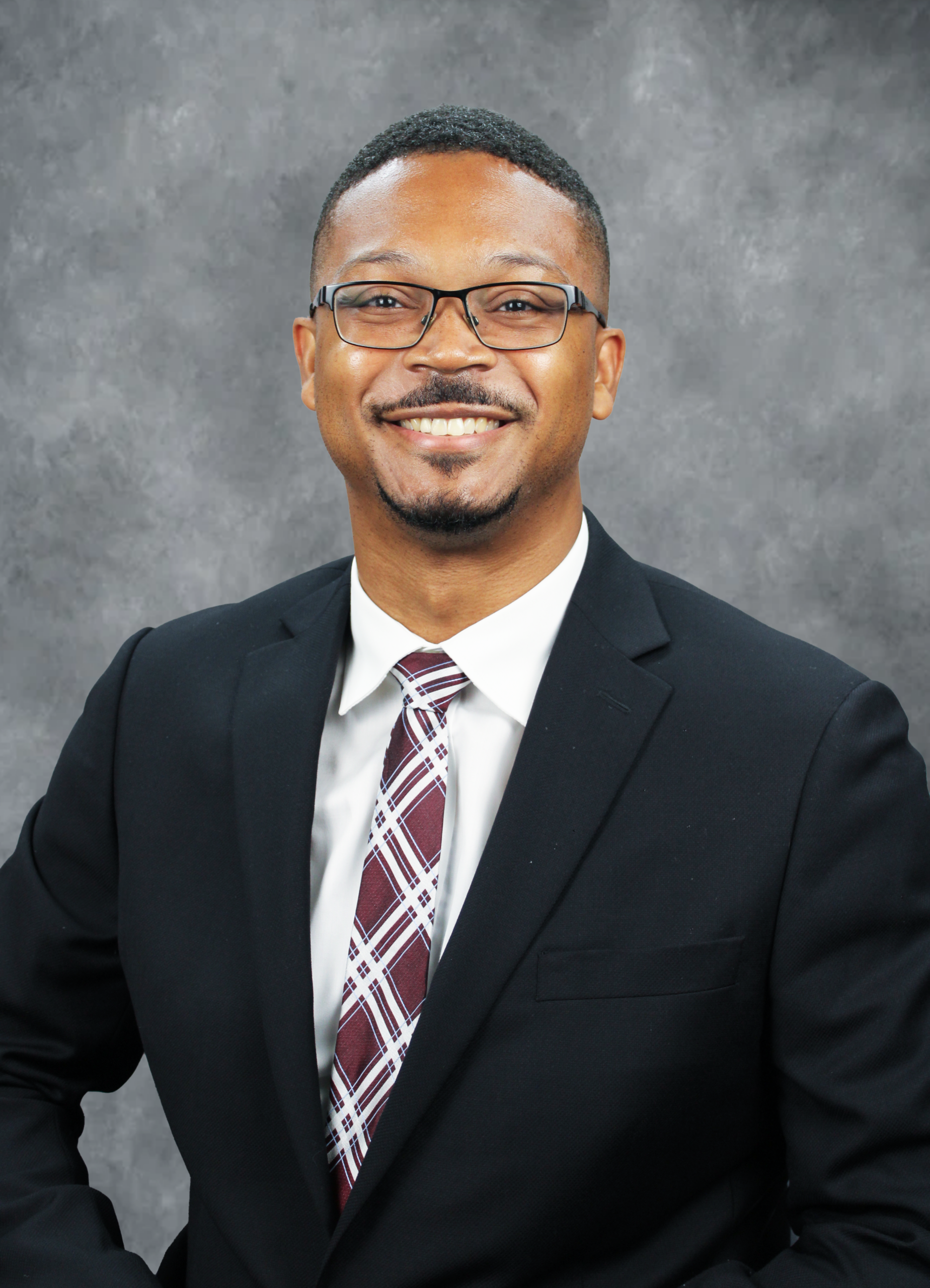 Man in suit standing against wall.