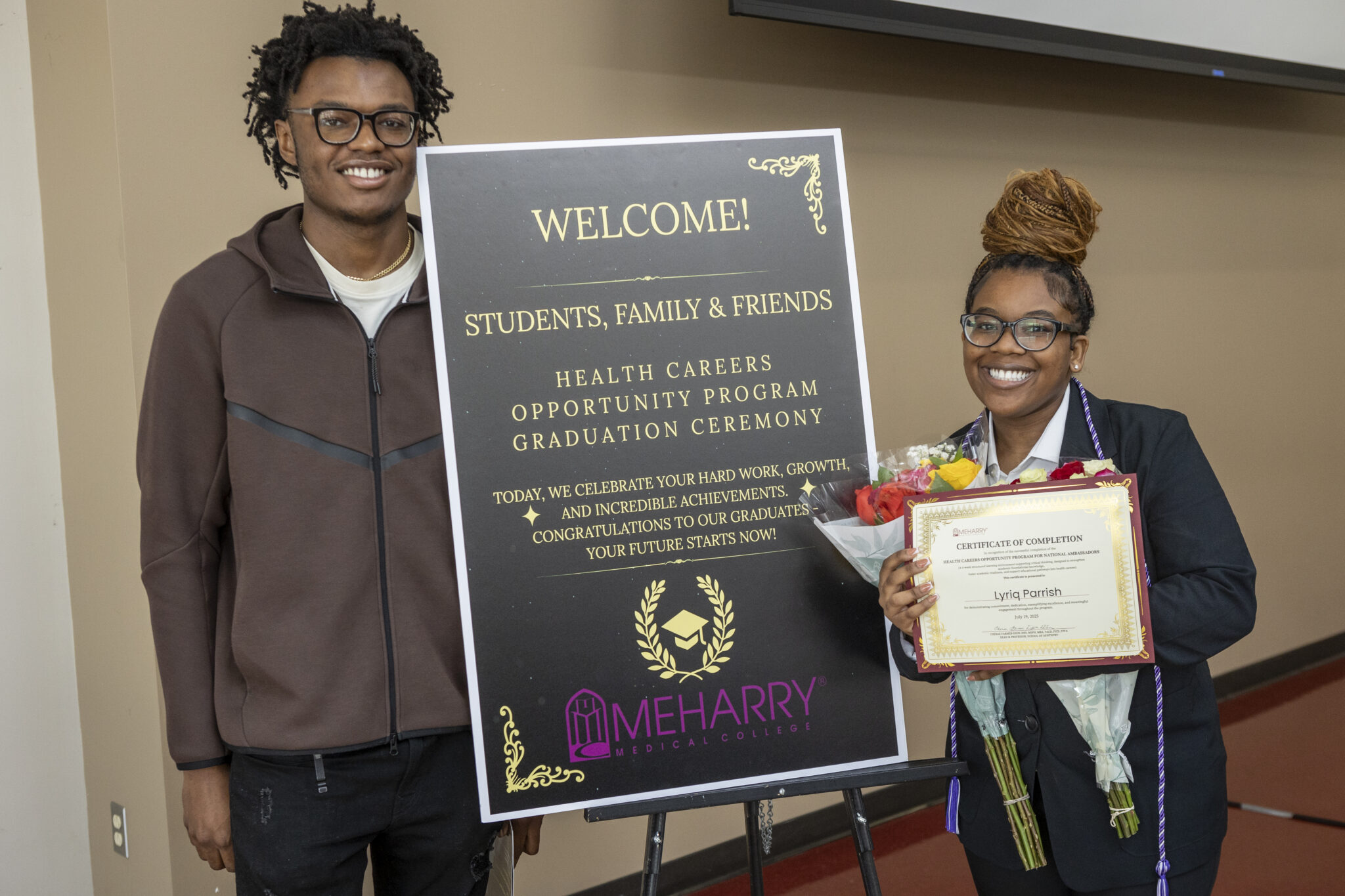 Two people holding certificates at an event.
