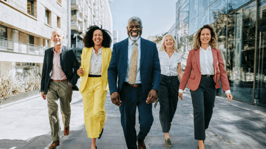 Five professionals walking together, smiling, dressed in business attire.