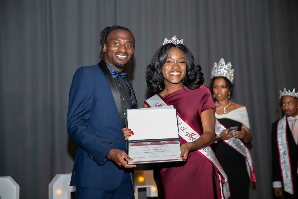 Man and woman holding award at ceremony.