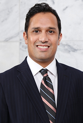 Man in suit standing against marble wall.