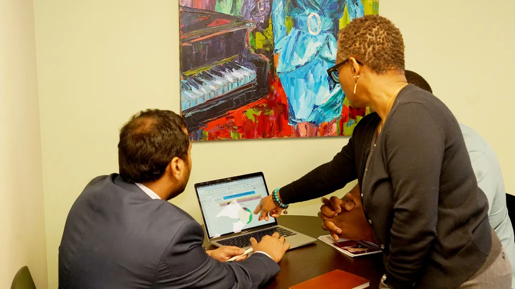 three staff examine data analysis on laptop