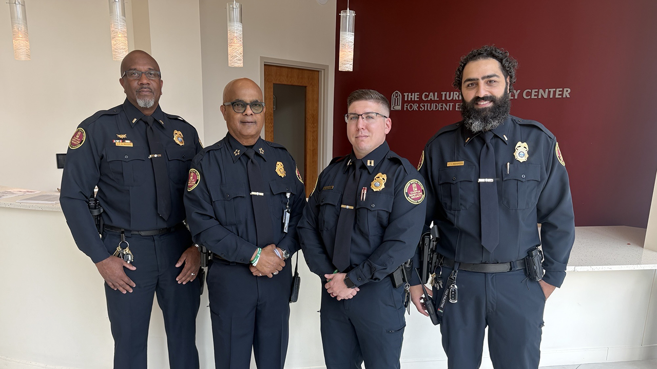 Four police officers standing in front of a sign.